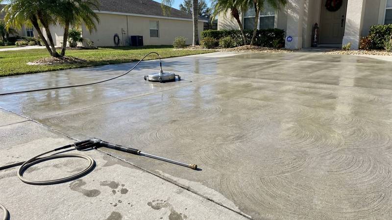 Example of driveway pressure washing in Holiday, FL — after soft washing. Concrete driveway - oil + tire stains. Surface cleaner, no zebra stripes.