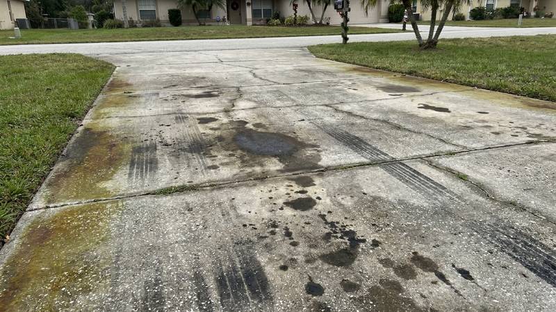 Example of driveway pressure washing in Holiday, FL — before soft washing. Concrete driveway - oil + tire stains. Surface cleaner, no zebra stripes.
