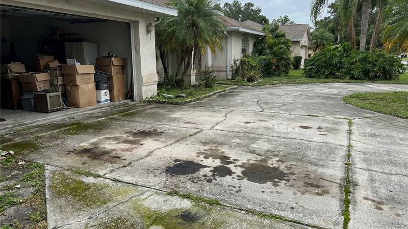 Example of driveway pressure washing in Clearwater, FL — before soft washing. Concrete - rust stains + tire marks. Even-pressure surface cleaner.
