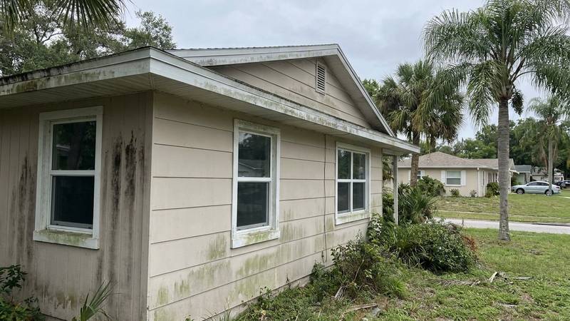Example of house washing in Palm Harbor, FL — before soft washing. Hardie board - window frames, eaves, and downspouts detailed.